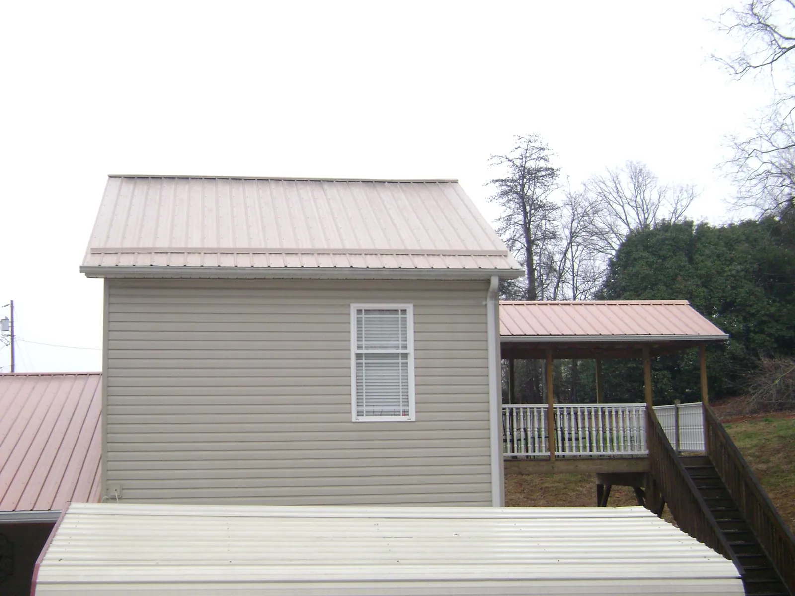 Tan metal roofs on a two story addition and attached porch, from a Roof Replacement job in Battle Creek